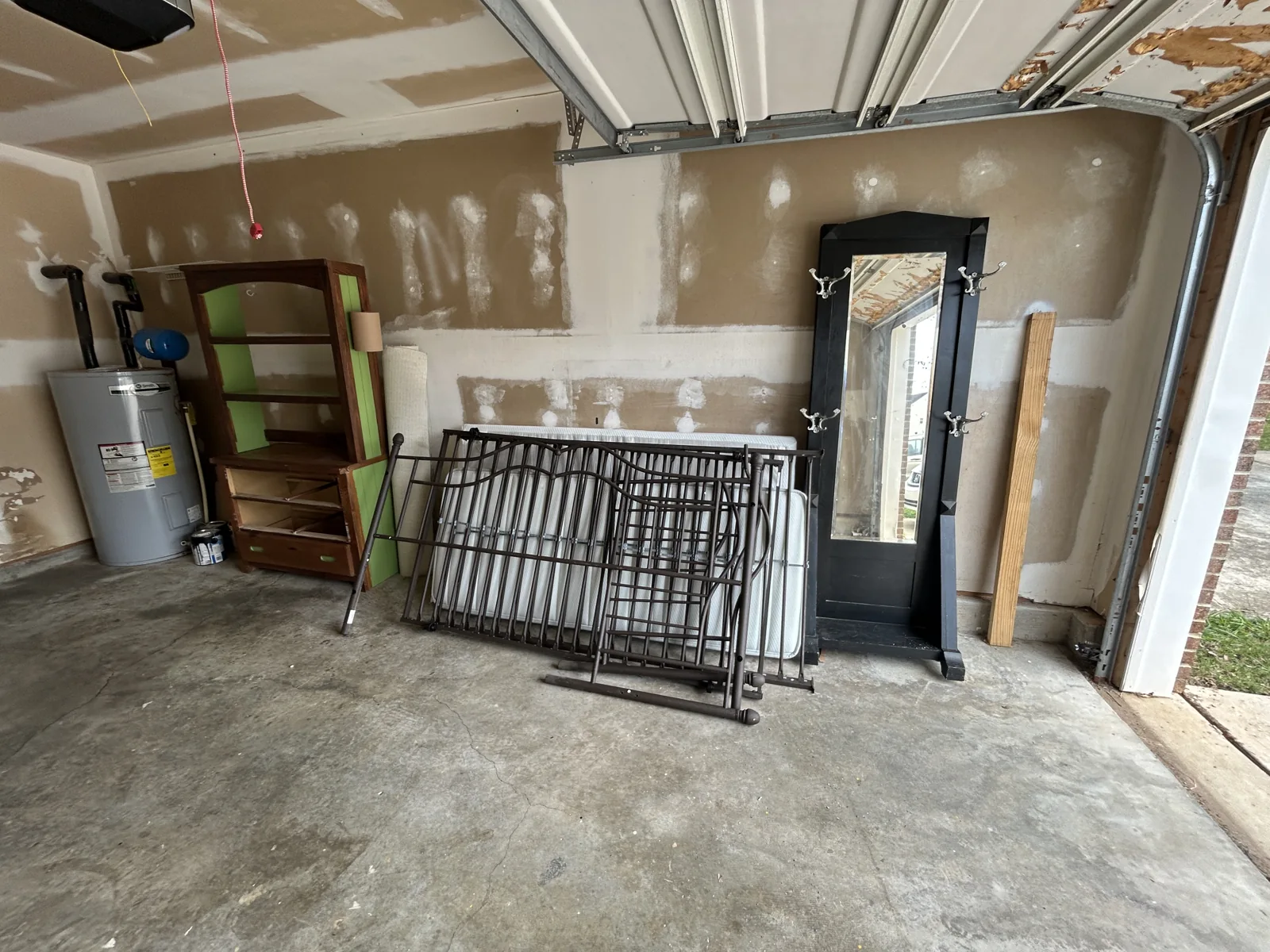 Before removal: furniture and shelving stacked along the garage wall — ACG Junk & Debris